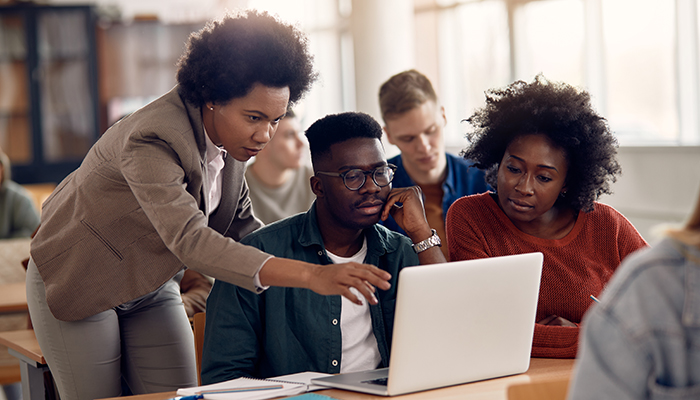 African American professor and her students using laptop during lecture in the classroom.